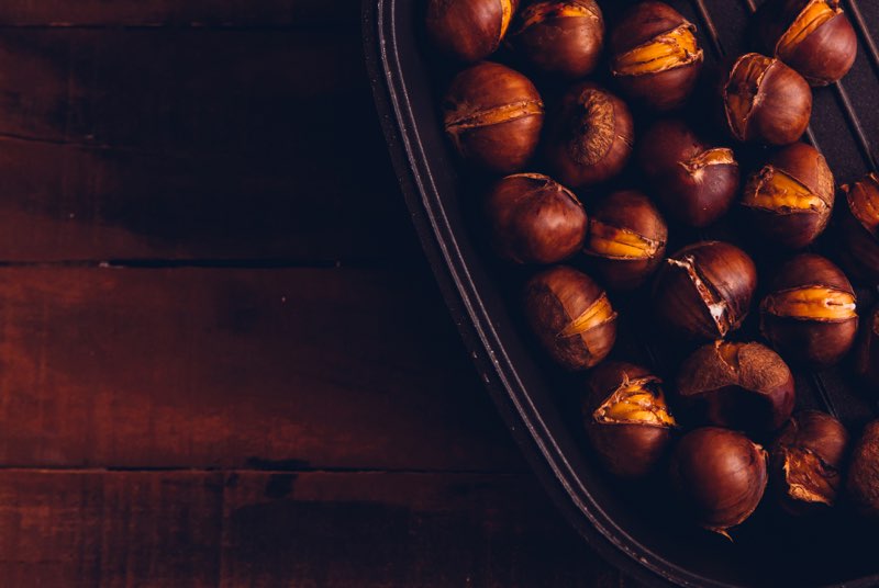 Chestnuts in a bowl flat lay on a dark wooden background free space for your text